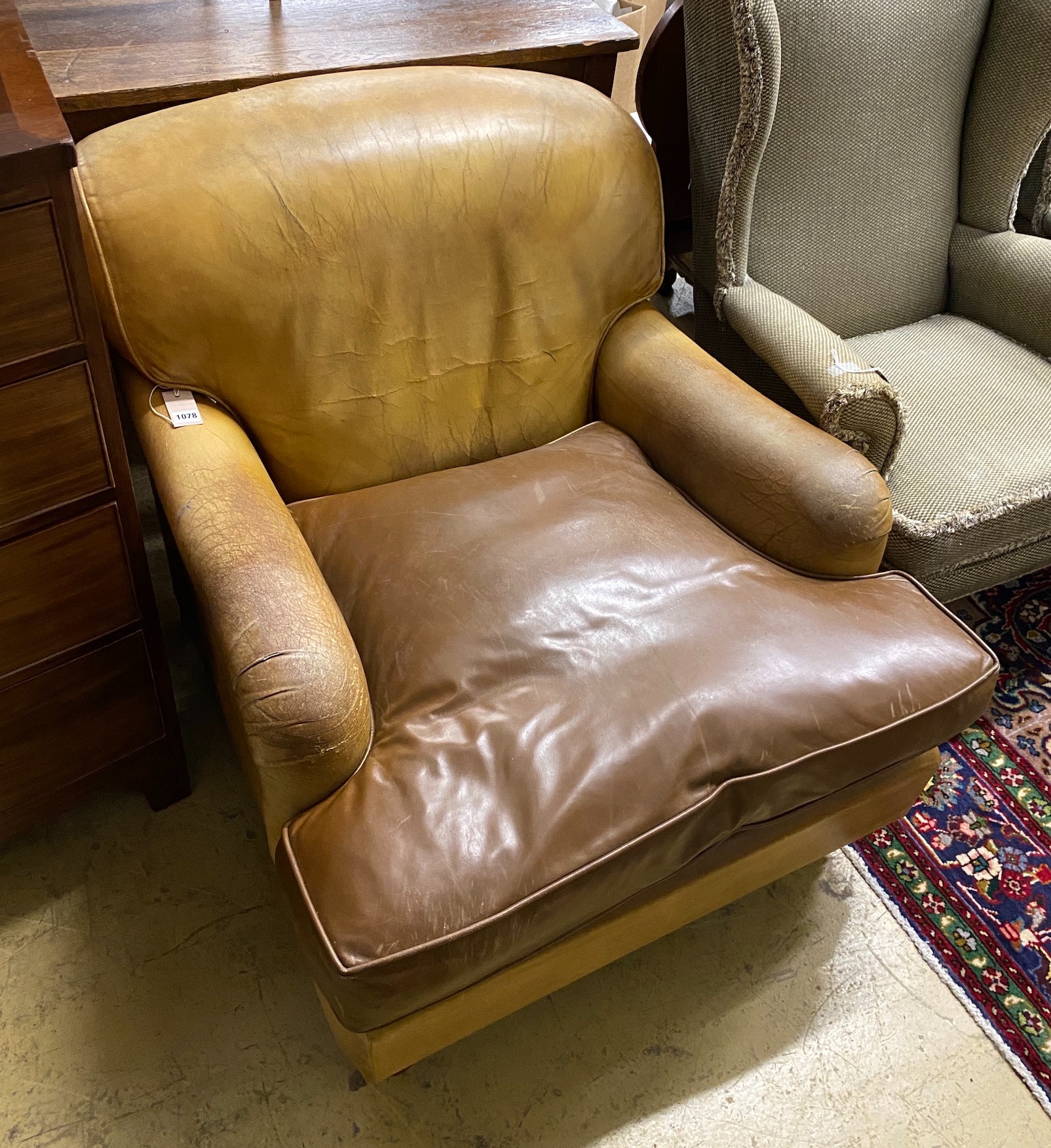 A Howard style faded brown leather club armchair, width 86cm, depth 108cm, height 74cm